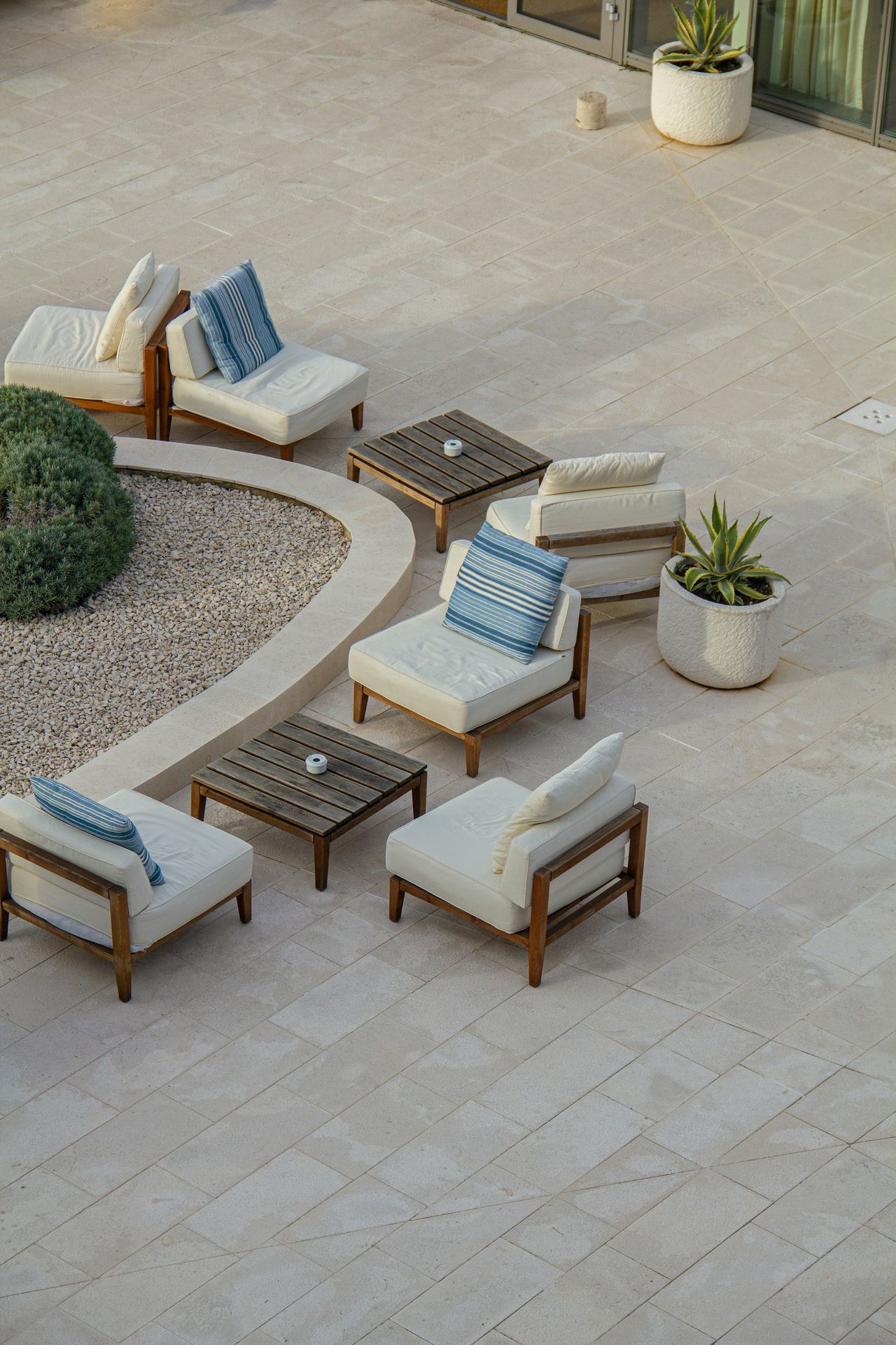 Outdoor seating area with woven chairs, tables, and garden décor arranged in a landscaped setting